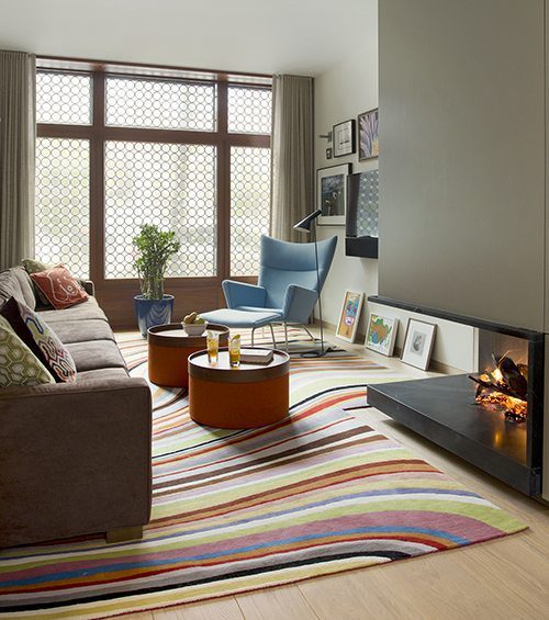 hardwood floor with Bold pattern rug accenting neutral fireplace